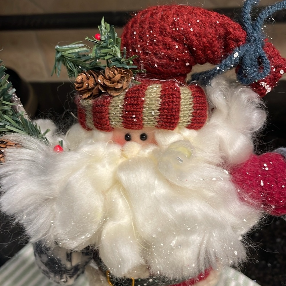Father Christmas stands proudly with his fluffy beard, pine branches and snow
